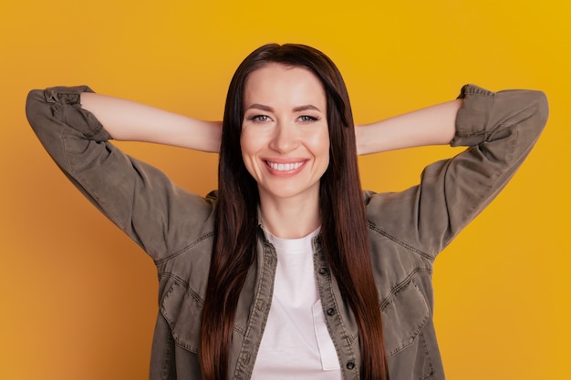 Portrait de femme positive rêvante tenir la tête par la main se détendre isolé sur fond jaune