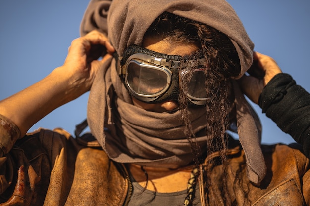 Portrait de femme post-apocalyptique à l'extérieur. Jeune guerrier fille mince dans des vêtements minables debout dans un