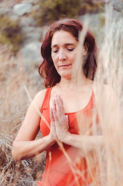 Portrait de femme avec une posture de gratitude et les yeux fermés dans le champ