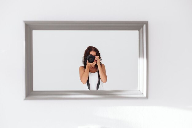 Photo portrait d'une femme prenant des photos par la fenêtre à la maison