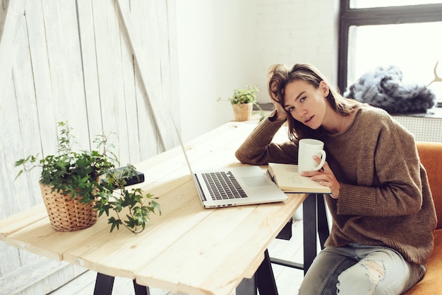 Portrait d'une femme prenant un verre avec un ordinateur portable à la table