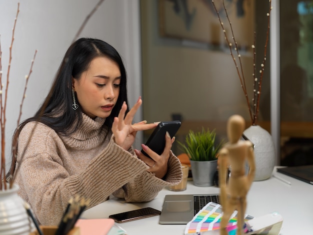 Portrait de femme en pull à l'aide d'un smartphone