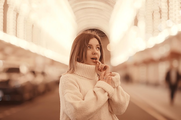 portrait d'une femme pull blanc hiver, saisonnier à l'extérieur de la ville promenade dans la ville du soir