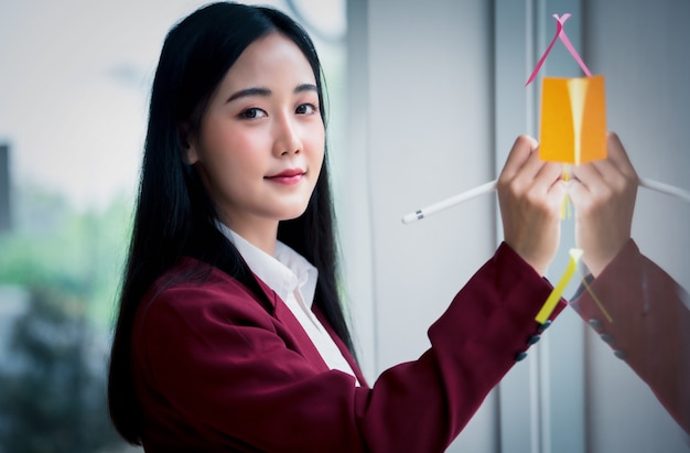 Portrait D'une Femme Qui écrit Sur Un Bloc De Papier Collant Sur La Paroi De Verre