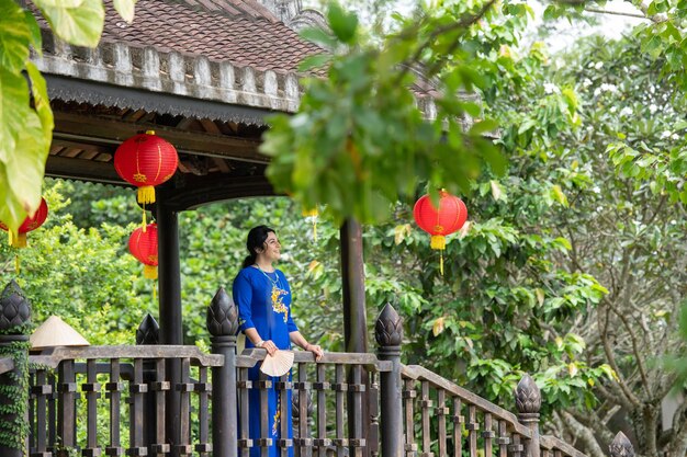 Photo portrait d'une femme de race blanche à ao dai sur le pont en bois