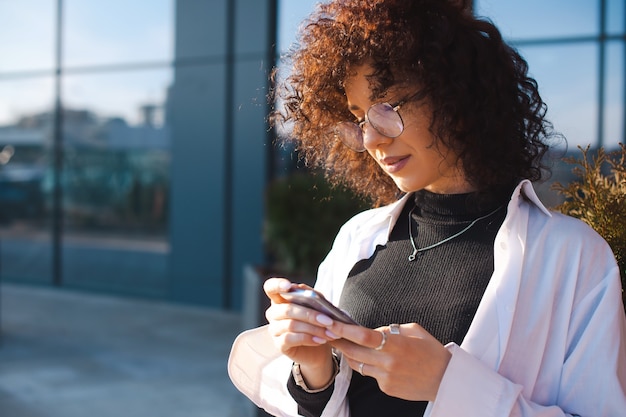 Portrait d'une femme regardant vers le bas une jeune femme frisée portant des lunettes et écrivant des messages