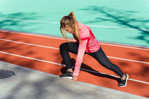 Portrait d'une femme de remise en forme faisant des exercices d'étirement au stade