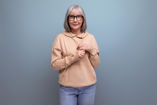 Portrait d'une femme rêveuse d'âge moyen aux cheveux gris dans un look décontracté sur un fond de studio avec