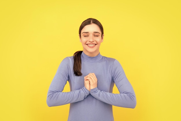 Portrait de femme rêveuse sur fond jaune faire voeu