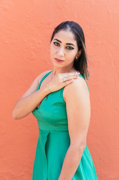 Portrait d'une femme en robe debout devant un mur rouge.