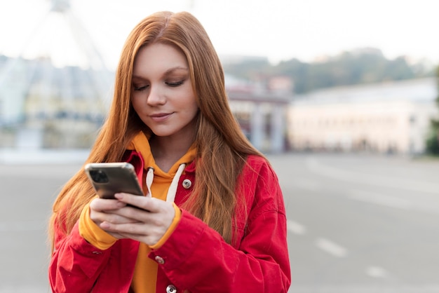 Photo portrait de femme rousse regardant son téléphone