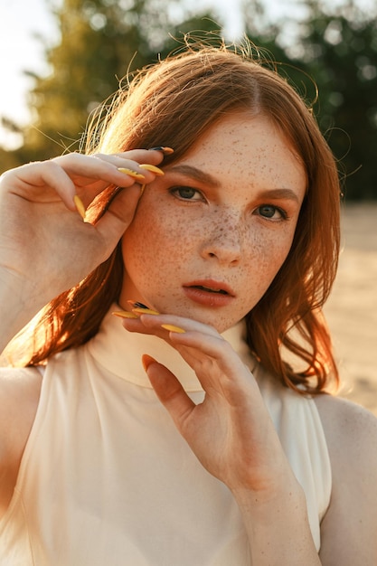 portrait de femme rousse avec des taches de rousseur touchant le visage