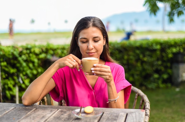 Portrait d'une femme russe souriante buvant un cappuccino chaud et regardant à gauche