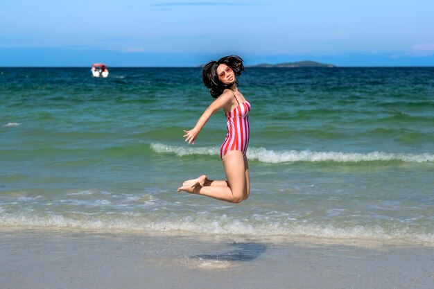 Photo portrait d'une femme sautant sur la plage