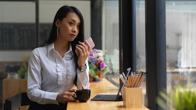 Portrait de femme se reposer avec une tasse de café et en regardant à travers la fenêtre de cafe