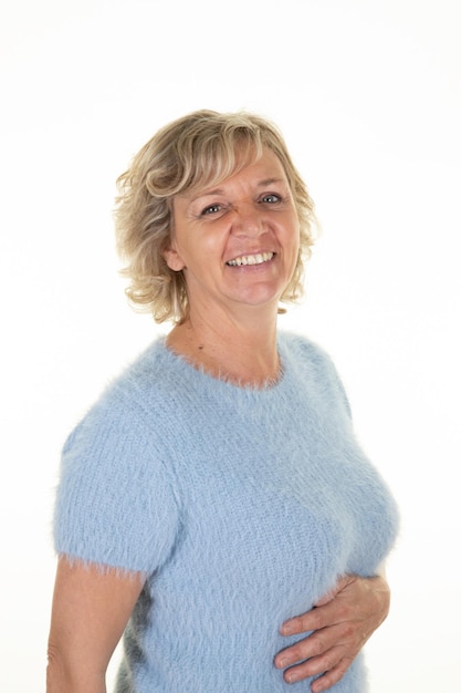 Portrait de femme senior blonde en laine pull bleu sur fond blanc