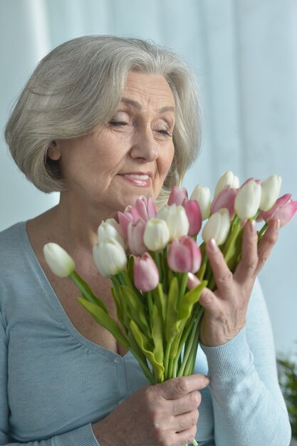 Portrait de femme senior avec des fleurs de tulipes en fleurs