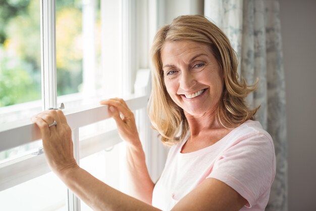 Portrait de femme senior heureuse debout à côté de la fenêtre