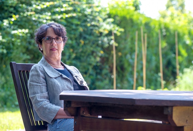 Portrait de femme senior avec des lunettes, assis dans le jardin