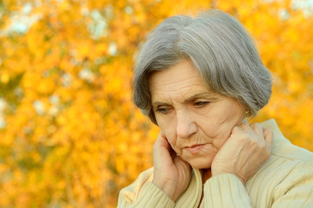 Portrait de femme senior pensant dans le parc d'automne