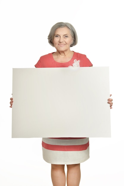 Portrait de femme senior en robe rouge avec une affiche blanche sur fond blanc