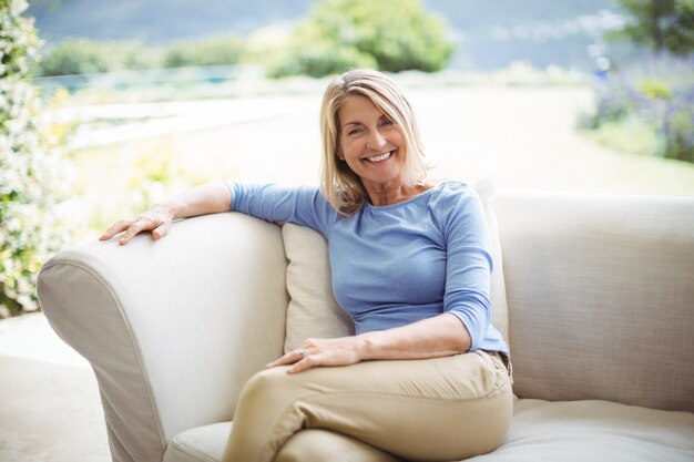 Portrait de femme senior souriante assise sur un canapé dans le salon