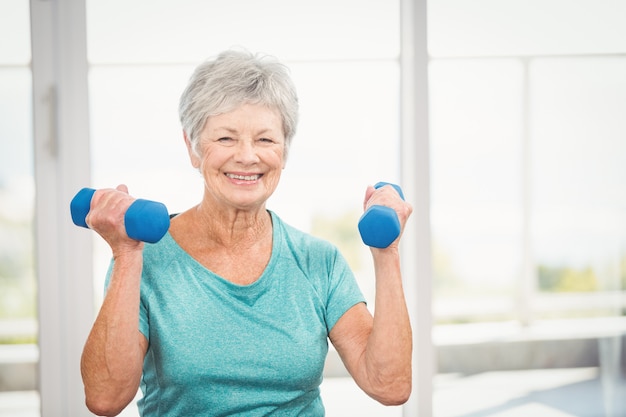 Portrait de femme senior souriante tenant des haltères