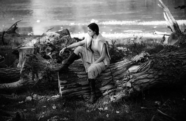 Portrait d'une femme sérieuse sur un tronc de bois Une jeune femme posant Une œuvre d'art d'une fille romantique Modèle sensuelle à la peau lisse et au maquillage dans une robe courte Place pour le texte Modèle de tendresse assez
