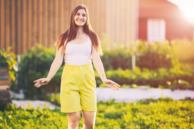 Portrait d'une femme en short jaune de bermude, une femme blanche d'un an posant pour un photographe près