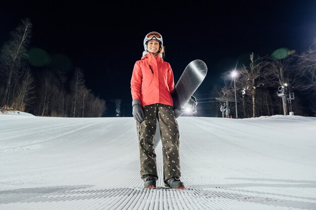 Portrait de femme snowboarder à pente du soir. Concept de sports d'hiver