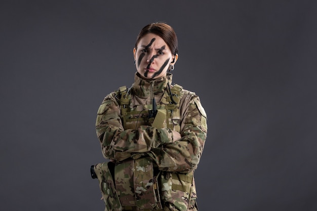 Portrait de femme soldat en camouflage sur le mur sombre