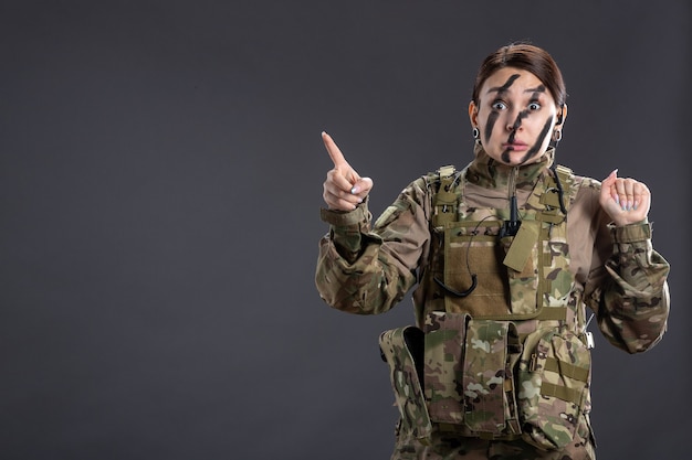 Portrait de femme soldat en uniforme militaire mur sombre