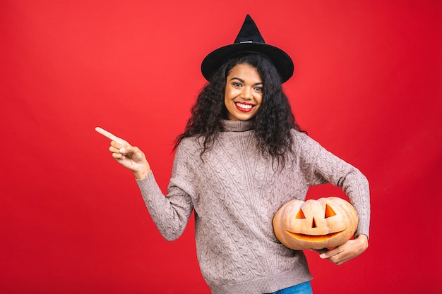 Portrait de femme sorcière afro-américaine Halloween tenant une citrouille