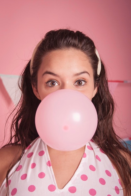 Portrait d'une femme soufflant un ballon rose