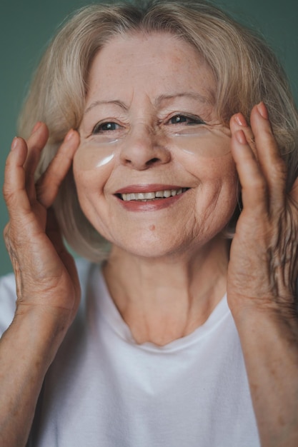 Portrait d'une femme souriante appliquant des pansements oculaires sur son visage tout en voulant avoir une peau fraîche Traitement de beauté Femme visage soins de la peau cosmétique Soins du corps