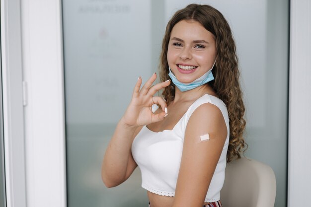 Portrait d'une femme souriante après avoir reçu le vaccin covid femme donnant un signe de la main ok et lui montrant