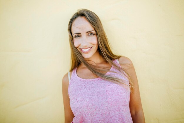 Portrait de femme souriante au mur jaune