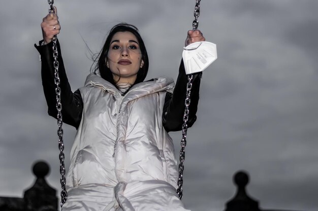 Portrait de femme souriante sur une balançoire la nuit Gros plan d'une jeune femme souriante sur une balançoire Concept d'une femme s'amusant sur une balançoire