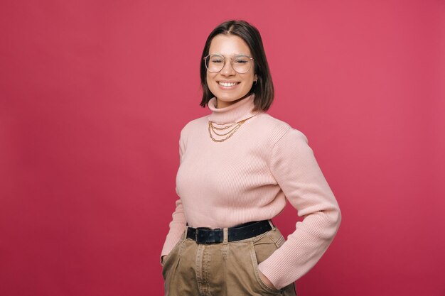 Portrait d'une femme souriante à la caméra debout avec les mains dans ses poches