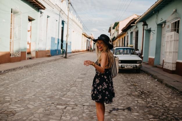 Portrait d'une femme souriante dans un chapeau debout au milieu des maisons