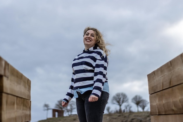 Portrait d'une femme souriante debout à l'extérieur dans la nature entre deux structures en bois