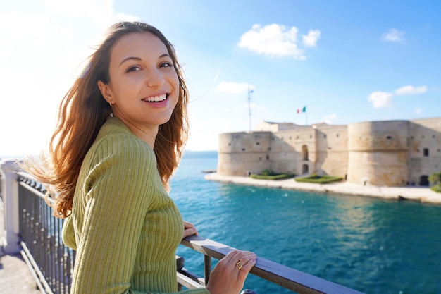 Portrait d'une femme souriante et détendue regardant la caméra avec le front de mer de Tarente sur l'arrière-plan Pouilles Italie