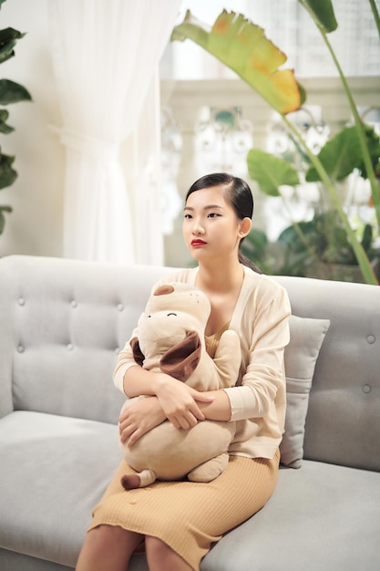 Photo portrait d'une femme souriante embrassant un chien jouet tout en se reposant sur le canapé à la maison