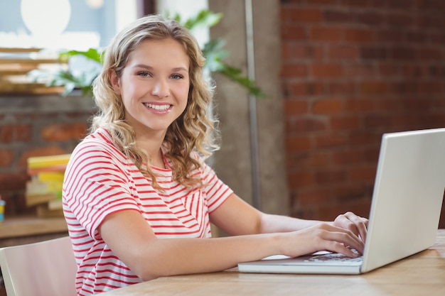 Portrait de femme souriante heureuse avec ordinateur portable au bureau