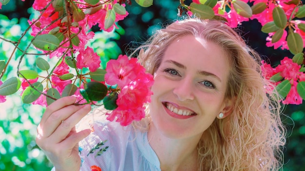 Photo portrait d'une femme souriante par des fleurs roses