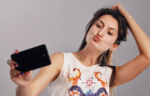 Portrait d'une femme souriante prenant une photo de selfie sur un téléphone intelligent