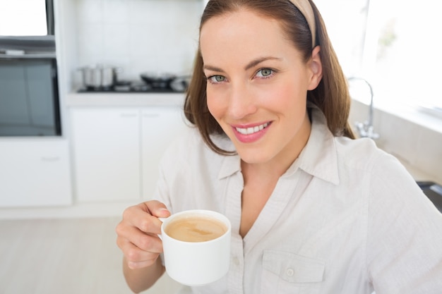 Portrait d&#39;une femme souriante avec une tasse de café dans la cuisine