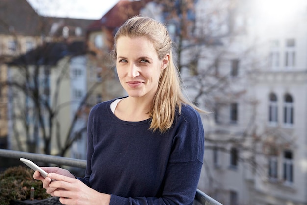 portrait, de, femme souriante, à, téléphone portable, sur, balcon