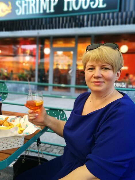 Photo portrait d'une femme souriante tenant une boisson sur la table d'un restaurant