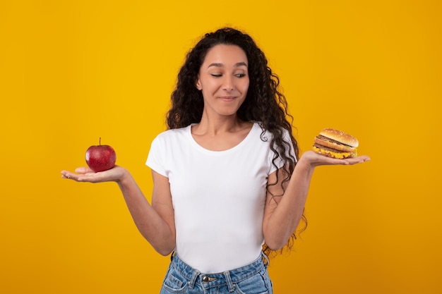Portrait de femme souriante tenant une pomme et un hamburger